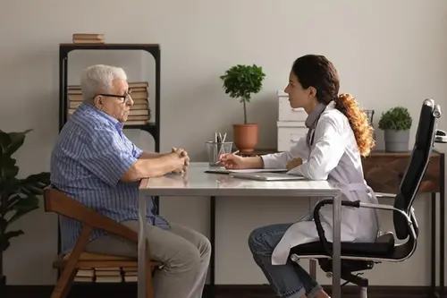 Äldre man och ung professionell kvinna sitter vid ett skrivbord och pratar
