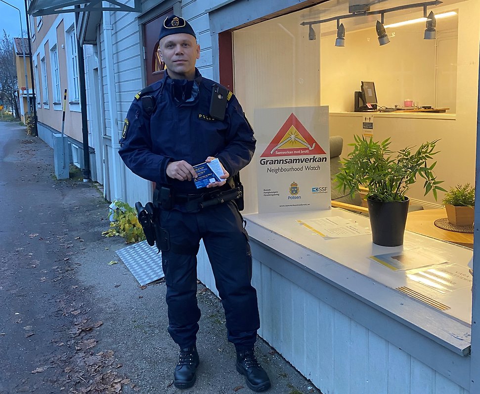 Kommunpolis Jörgen Wilestedt står i uniform utanför poliskontoret i Heby. Han håller i informationskort som ska delas ut till äldre personer.
