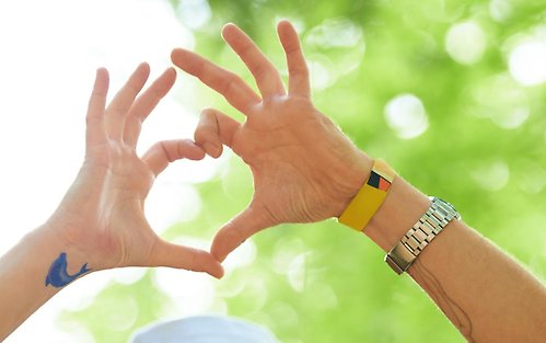 Två händer formar ett hjärta i solljuset.