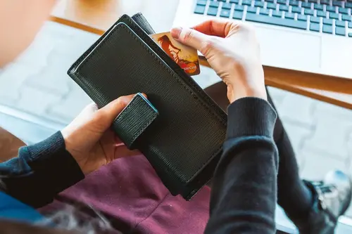 Kvinna plockar fram sitt kreditkort ur sin plånbok