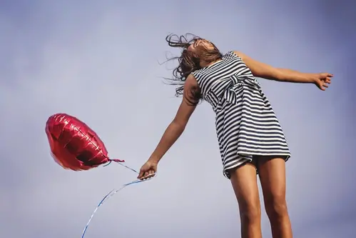 Ung tjej med ballong ser fri och lycklig ut
